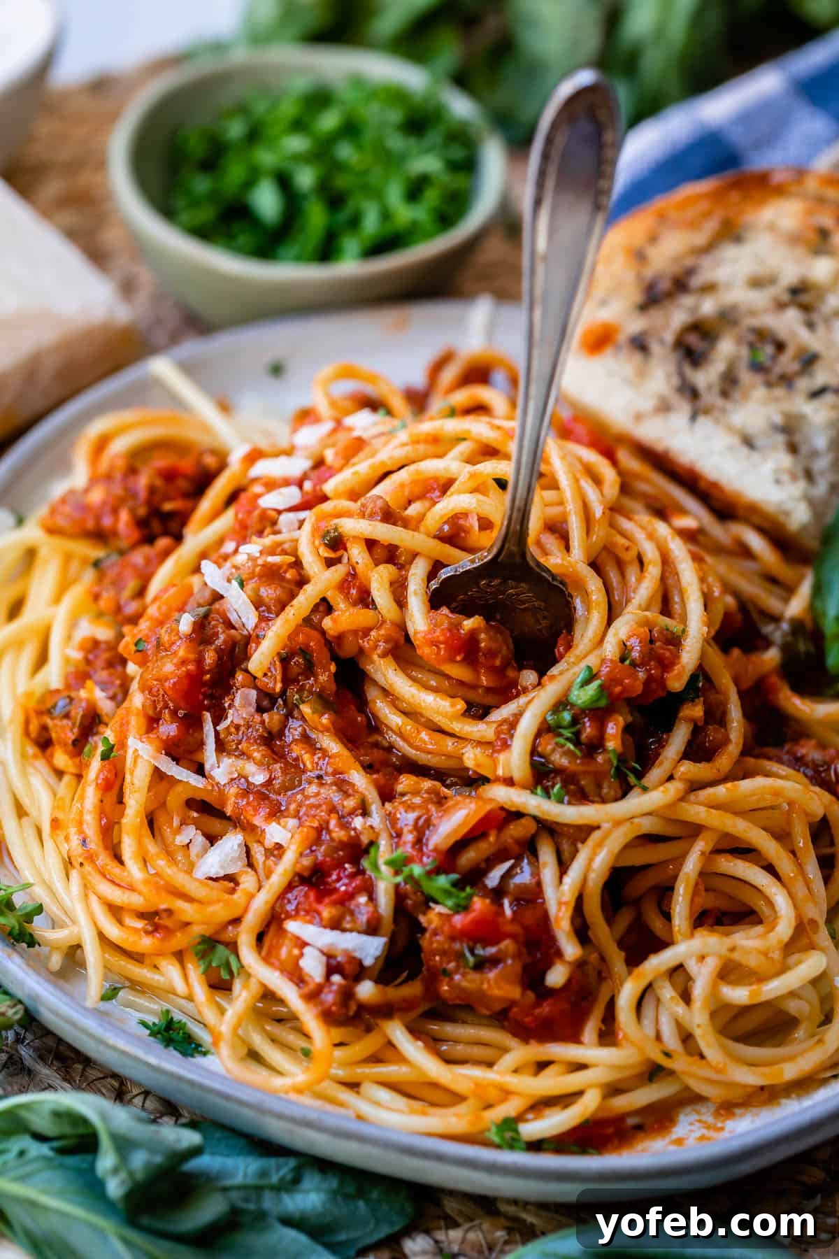 Effortless 30-Minute Spaghetti Sauce 4 A pristine white plate generously filled with spaghetti, exquisitely topped with a rich, easy homemade spaghetti sauce, a fork poised for enjoyment.