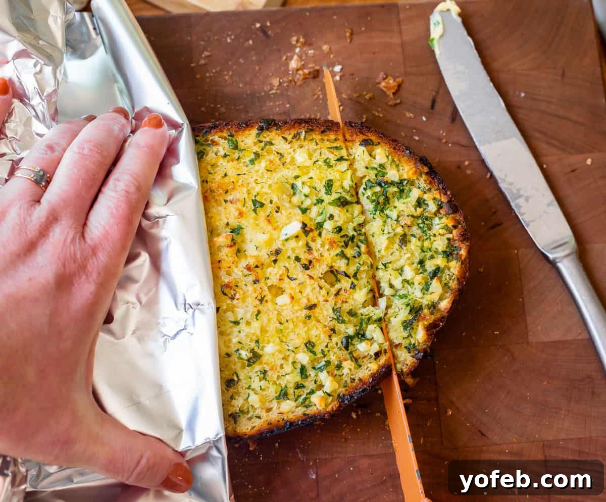 Irresistible Garlic Butter Loaf 19 A freshly baked half of the best garlic bread being expertly sliced with a bread knife on a cutting board.