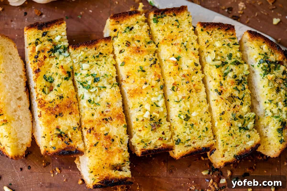 Irresistible Garlic Butter Loaf 20 Perfectly baked garlic bread, sliced and artfully arranged on a cutting board with a knife in the background.