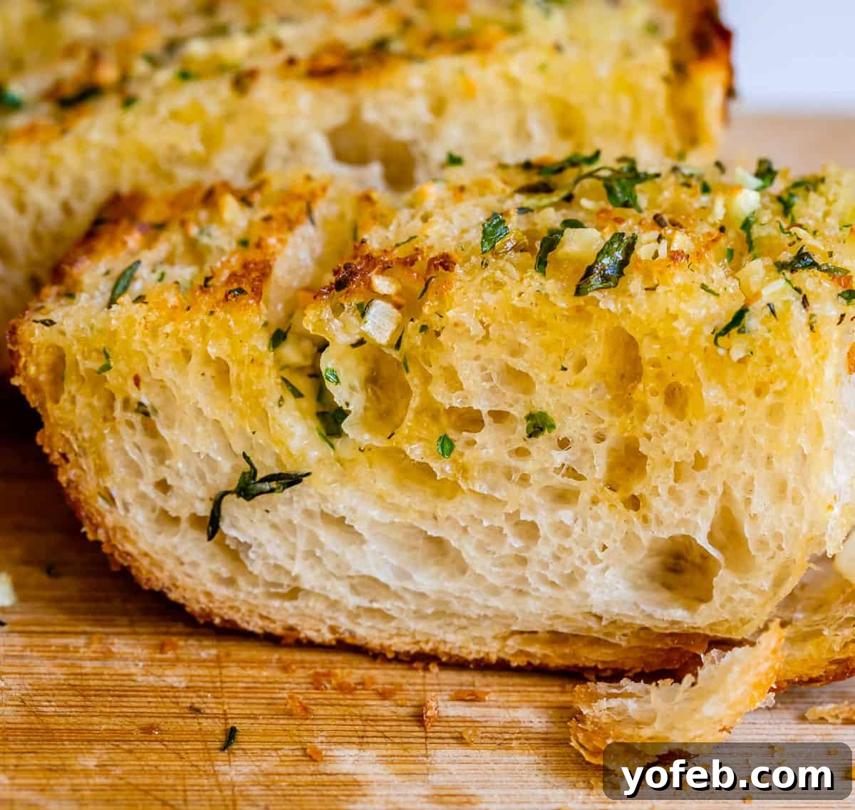 Irresistible Garlic Butter Loaf 3 Buttery homemade garlic bread, garnished with fresh parsley and minced garlic, arranged on a rustic cutting board.