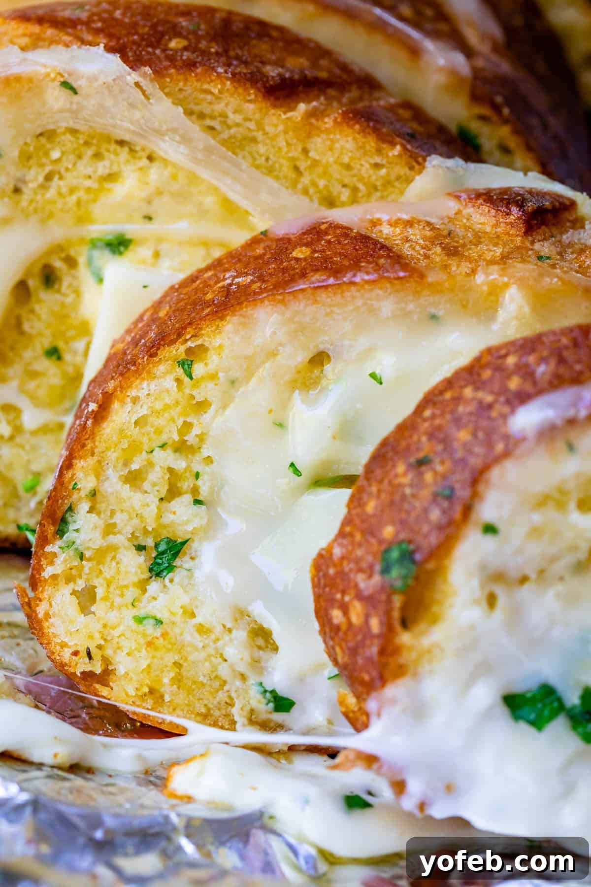Irresistible Garlic Butter Loaf 29 Upright cheesy bread, generously sprinkled with fresh parsley, arranged on foil and ready for the oven.