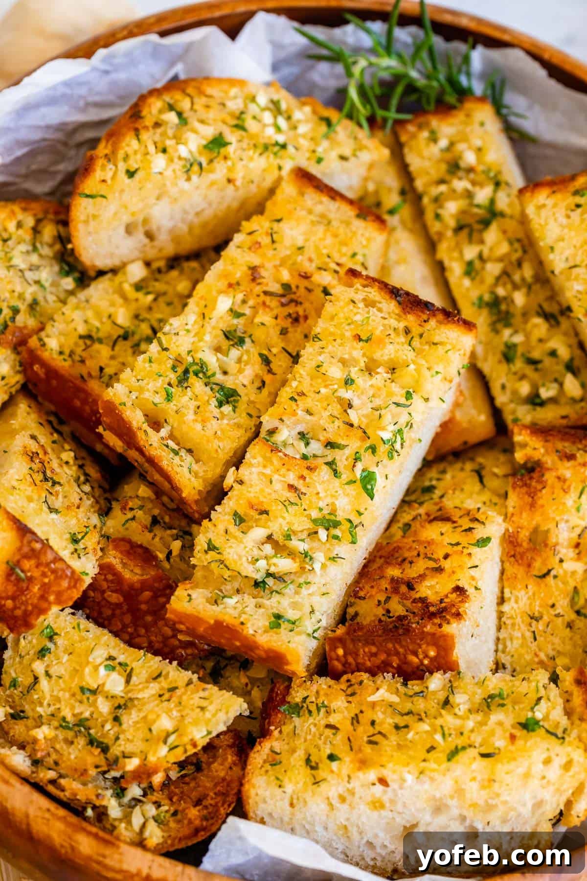 Irresistible Garlic Butter Loaf 4 Crispy garlic bread slices, perfectly toasted and piled high in a rustic wooden bowl, ready for serving.