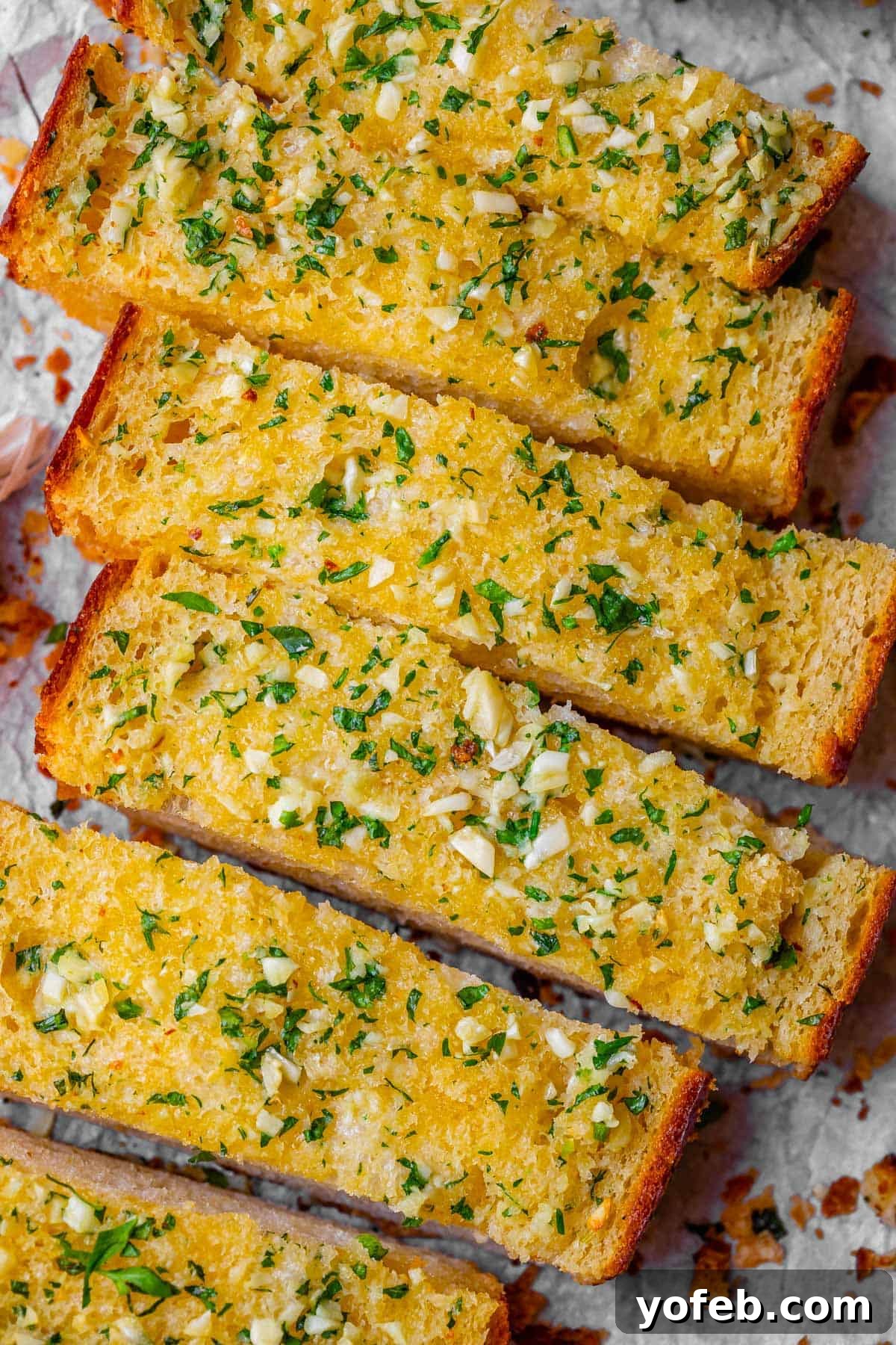 Irresistible Garlic Butter Loaf 5 The best garlic bread recipe, perfectly sliced and neatly lined up on parchment paper for presentation.