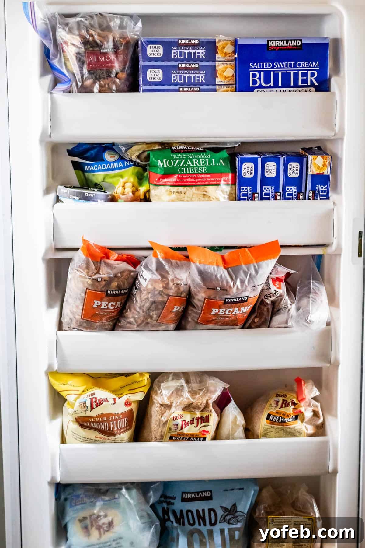 The Ultimate Guide to a Fully Stocked Pantry and Fridge 8 The door of a freezer, packed with an assortment of frozen goods including butter, pecans, cheese, almond flour, macadamia nuts, and other essentials.