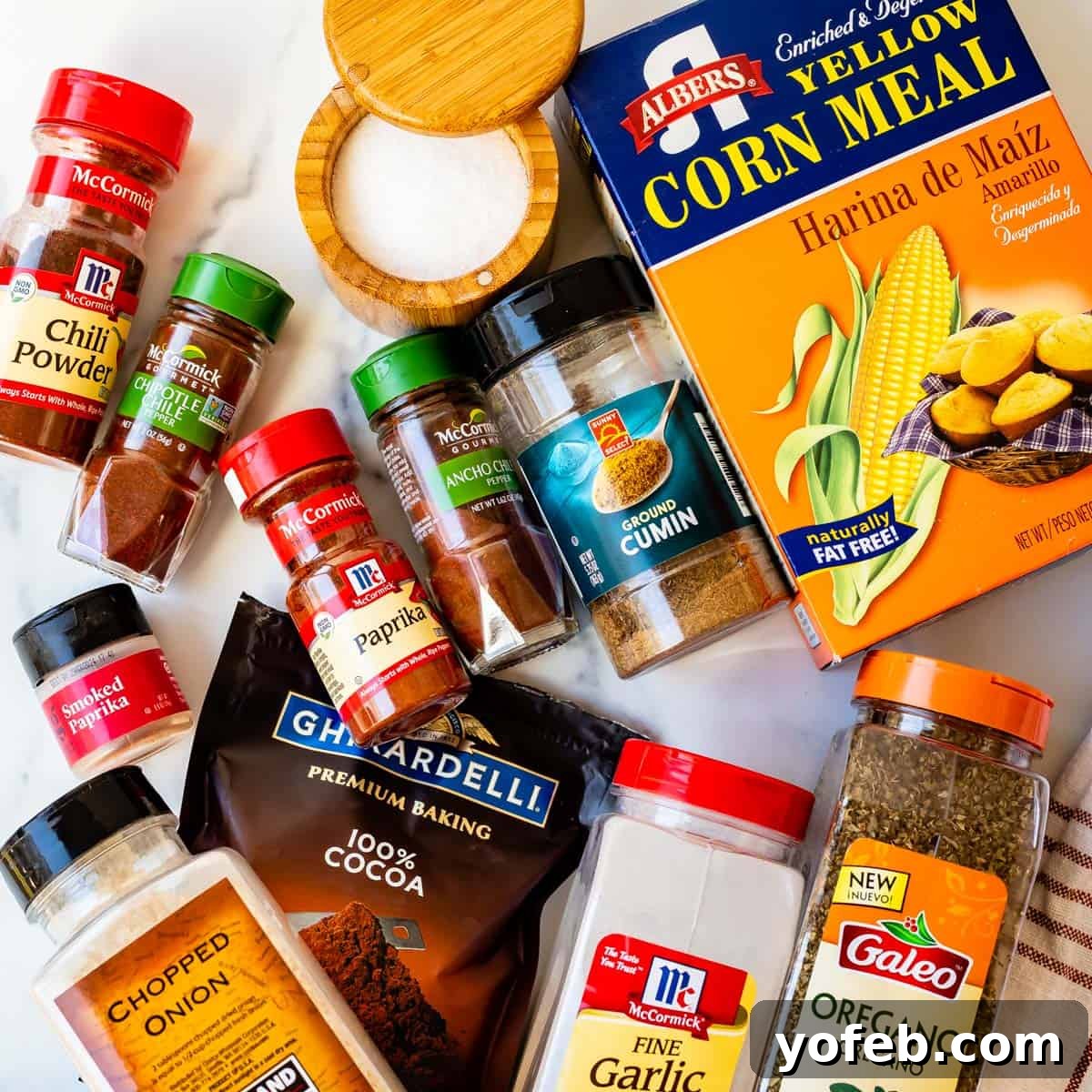 The Ultimate Guide to a Fully Stocked Pantry and Fridge 10 Various Mexican spices displayed in small containers alongside cornmeal spread out on a kitchen countertop.