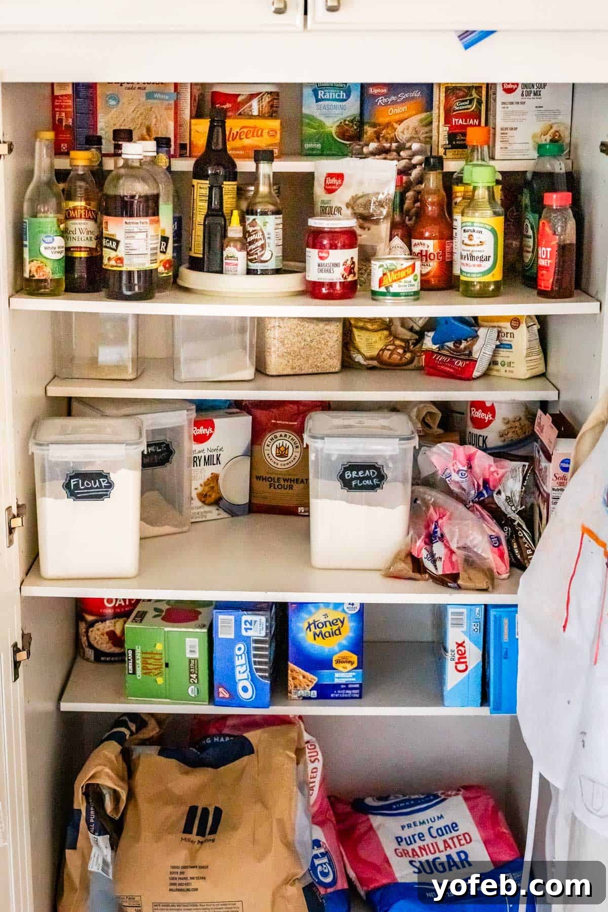 The Ultimate Guide to a Fully Stocked Pantry and Fridge 6 An open pantry showcasing shelves laden with bulk items like flour and sugar, alongside vinegar, maraschino cherries, honey, and brown sugar.