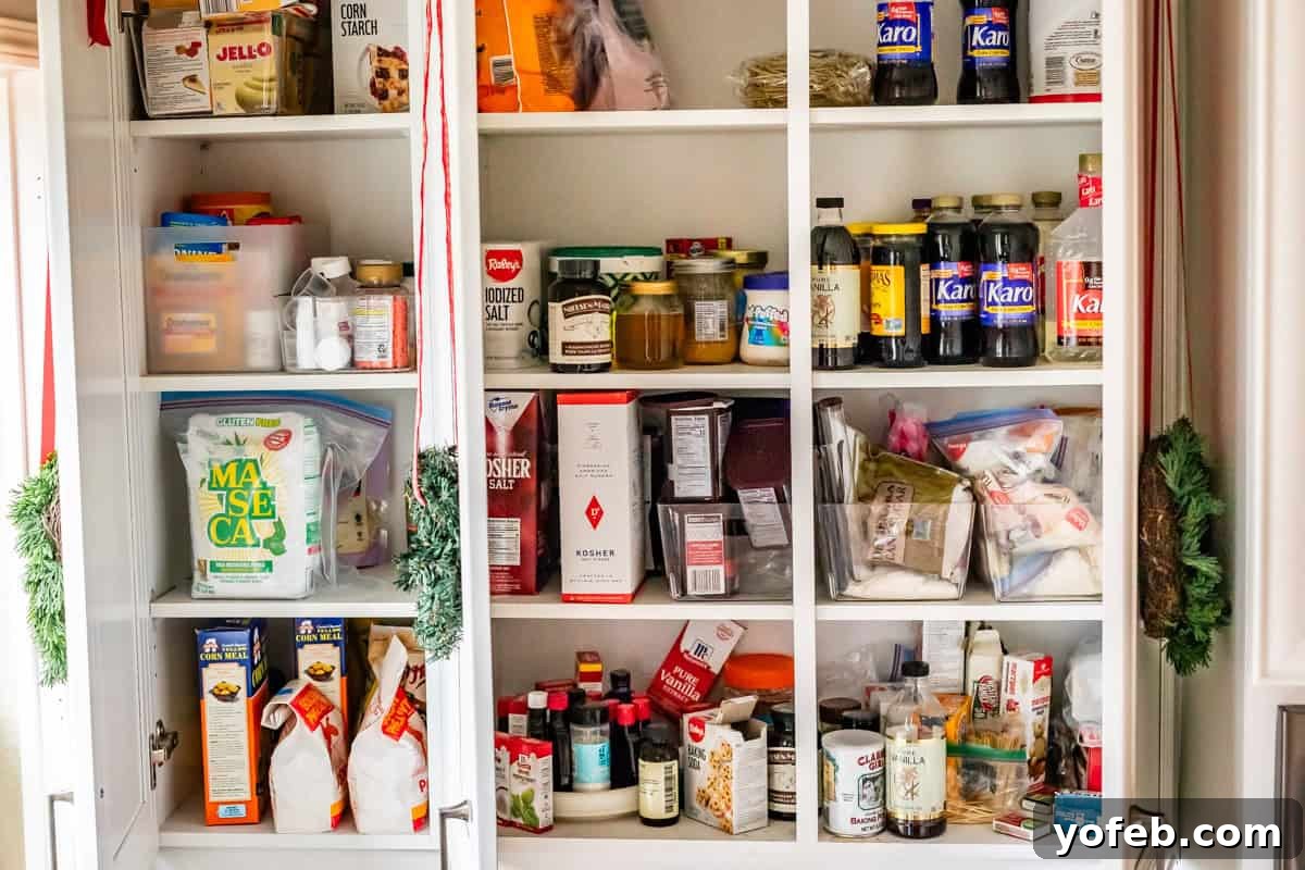 The Ultimate Guide to a Fully Stocked Pantry and Fridge 7 An open baking pantry revealing neatly organized bottles of vanilla, cornstarch, Maseca, Karo syrup, various extracts, and baking powder.