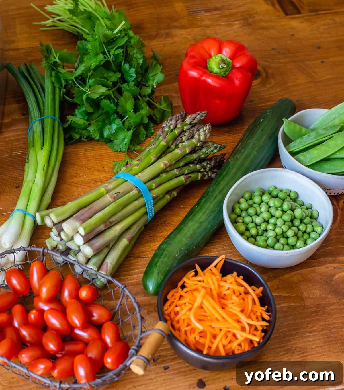 Vibrant Spring Sesame Noodles 12 A selection of colorful vegetables suitable for sesame noodles, including asparagus, peas, carrots, and bell pepper, arranged on a cutting board.