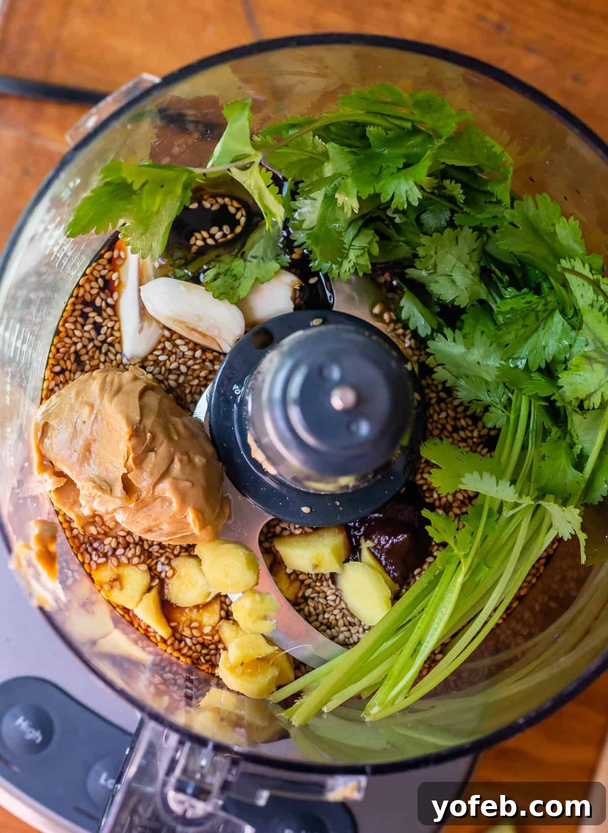 Vibrant Spring Sesame Noodles 9 Various sesame noodle sauce ingredients like sesame seeds, soy sauce, peanut butter, ginger, and garlic inside a food processor, ready to be blended.