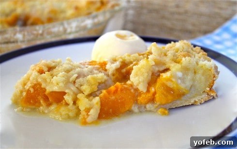 Golden Peach Dream Pie 3 A delectable piece of peach custard pie with a crumbly topping, served on a white plate alongside a scoop of vanilla ice cream, set against a rustic wooden table.