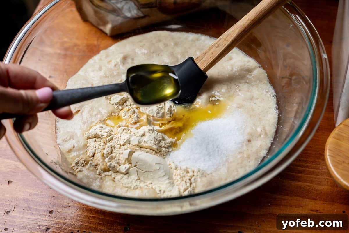 The White Bread Recipe That Ends Your Search 11 A glass mixing bowl with an activated yeast mixture, to which oil, sugar, and vital wheat gluten are being added for enhanced rise and flavor.