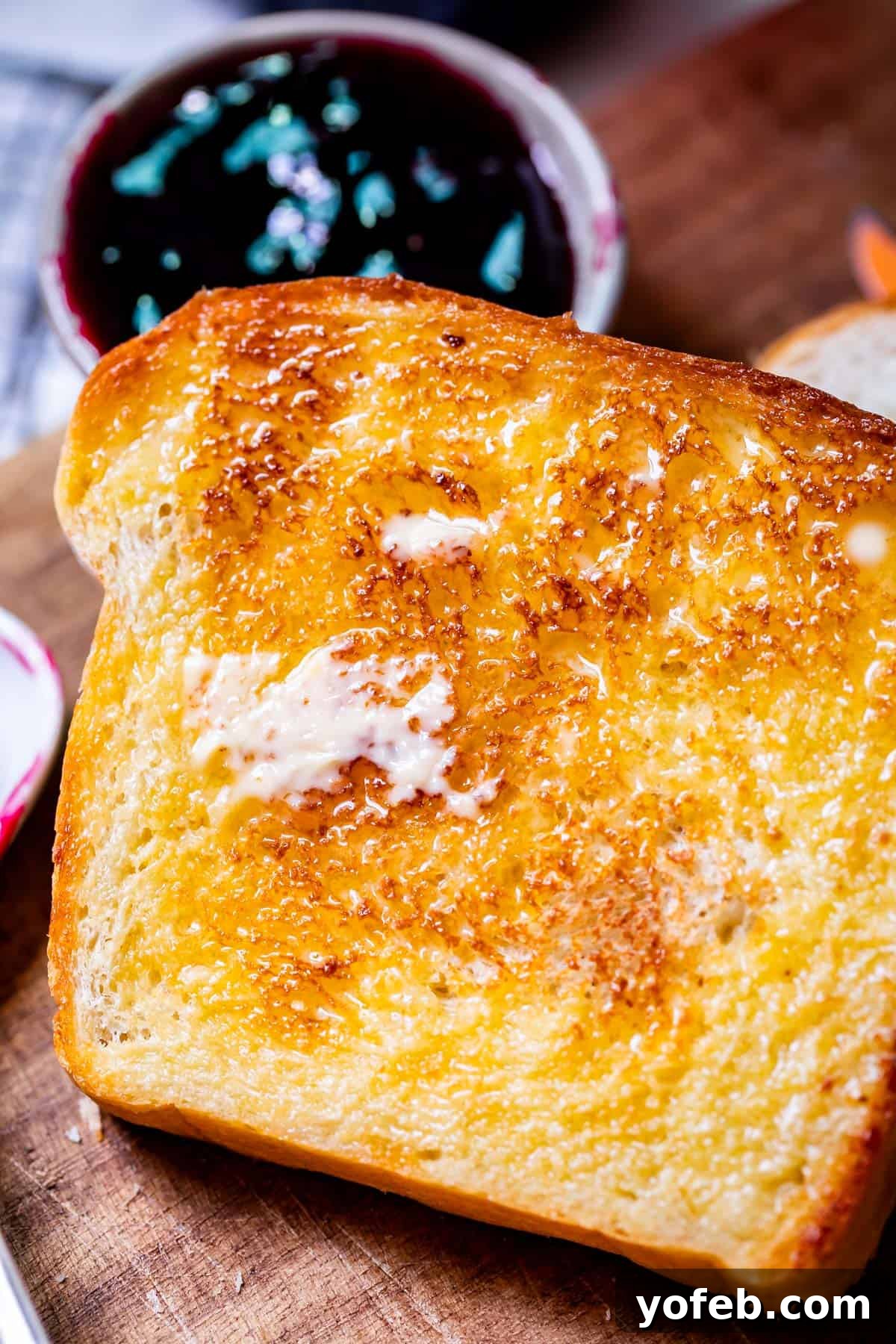The White Bread Recipe That Ends Your Search 4 A close-up of a golden toasted slice of homemade white bread, with butter generously melting into its soft nooks and crannies.