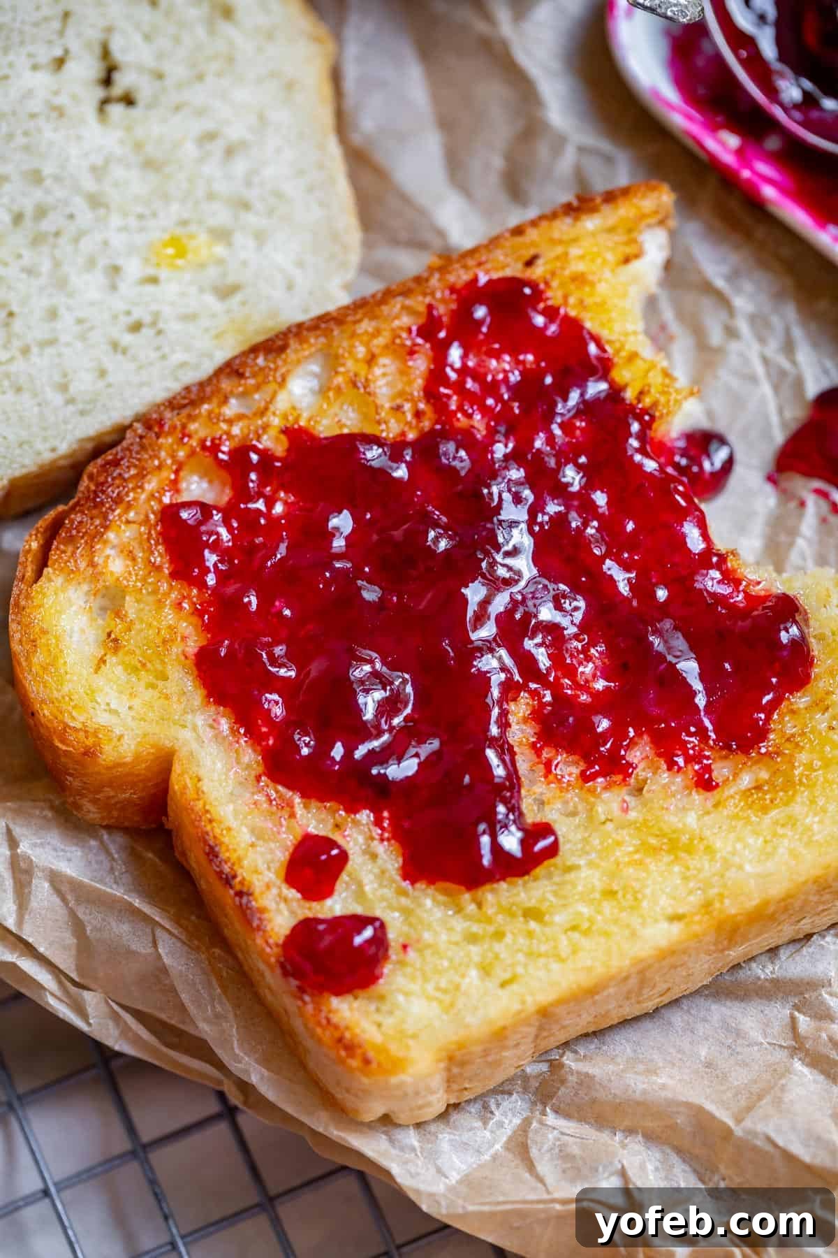 The White Bread Recipe That Ends Your Search 7 A delectable slice of toasted and buttered white bread, generously topped with a smear of vibrant jam.