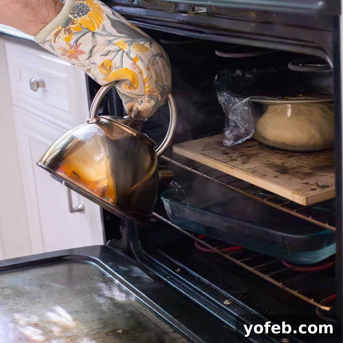 Decadent Bavarian Cream Donuts 11 pouring hot water from a kettle into a pyrex dish under bowl of donut dough in oven.