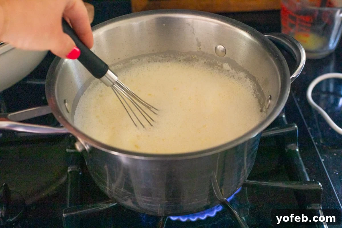Velvety Crème Pâtissière 12 pot with a whisk stirring pastry cream mixture, set over a hot stove to cook.