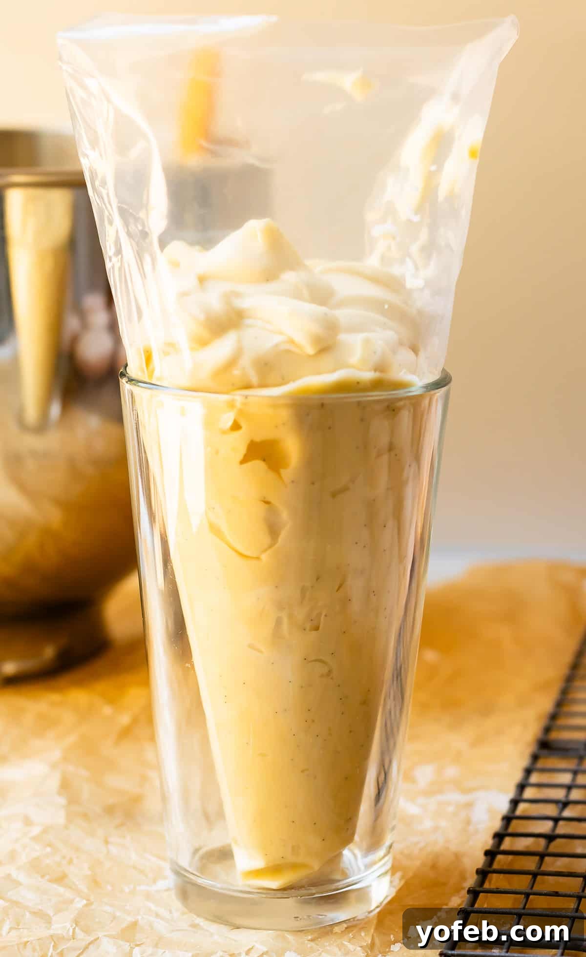 Velvety Crème Pâtissière 18 a drinking glass holding up a pastry bag that is filled with homemade pastry cream.