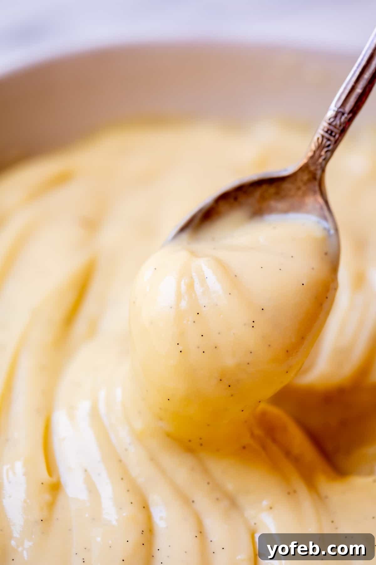 Velvety Crème Pâtissière 20 spoon holding up vanilla bean flecked Crème Pâtissière ready to be eaten.