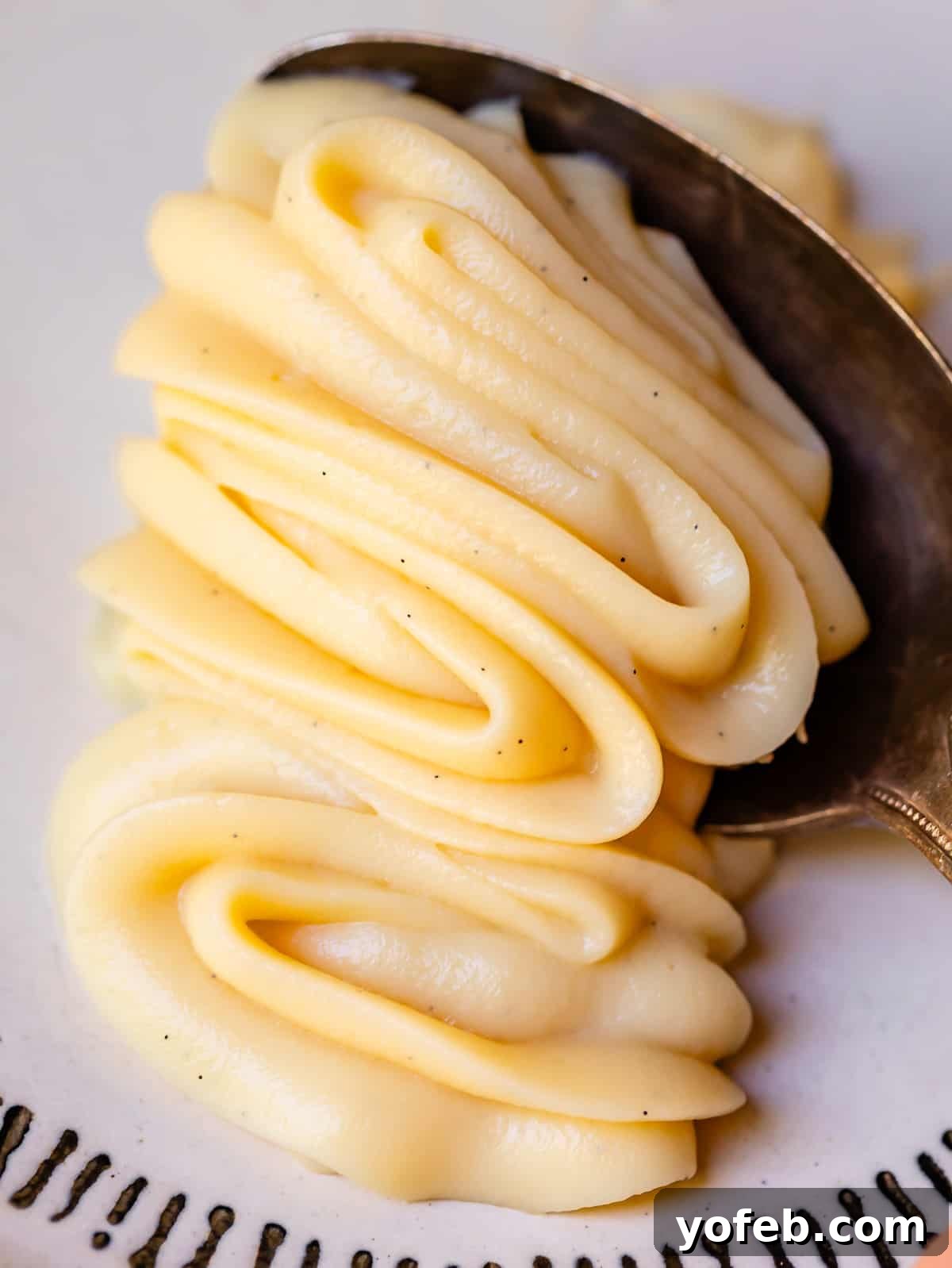 Velvety Crème Pâtissière 3 silver spoon scooping up some of the piped vanilla pastry cream and the shape holding.