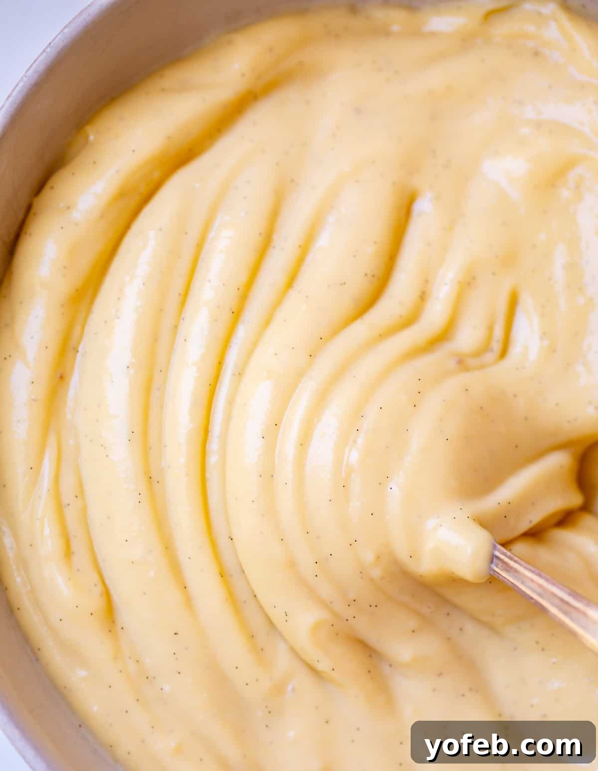 Velvety Crème Pâtissière 5 close up of spoon moving through ripples of thick pastry cream in a bowl.