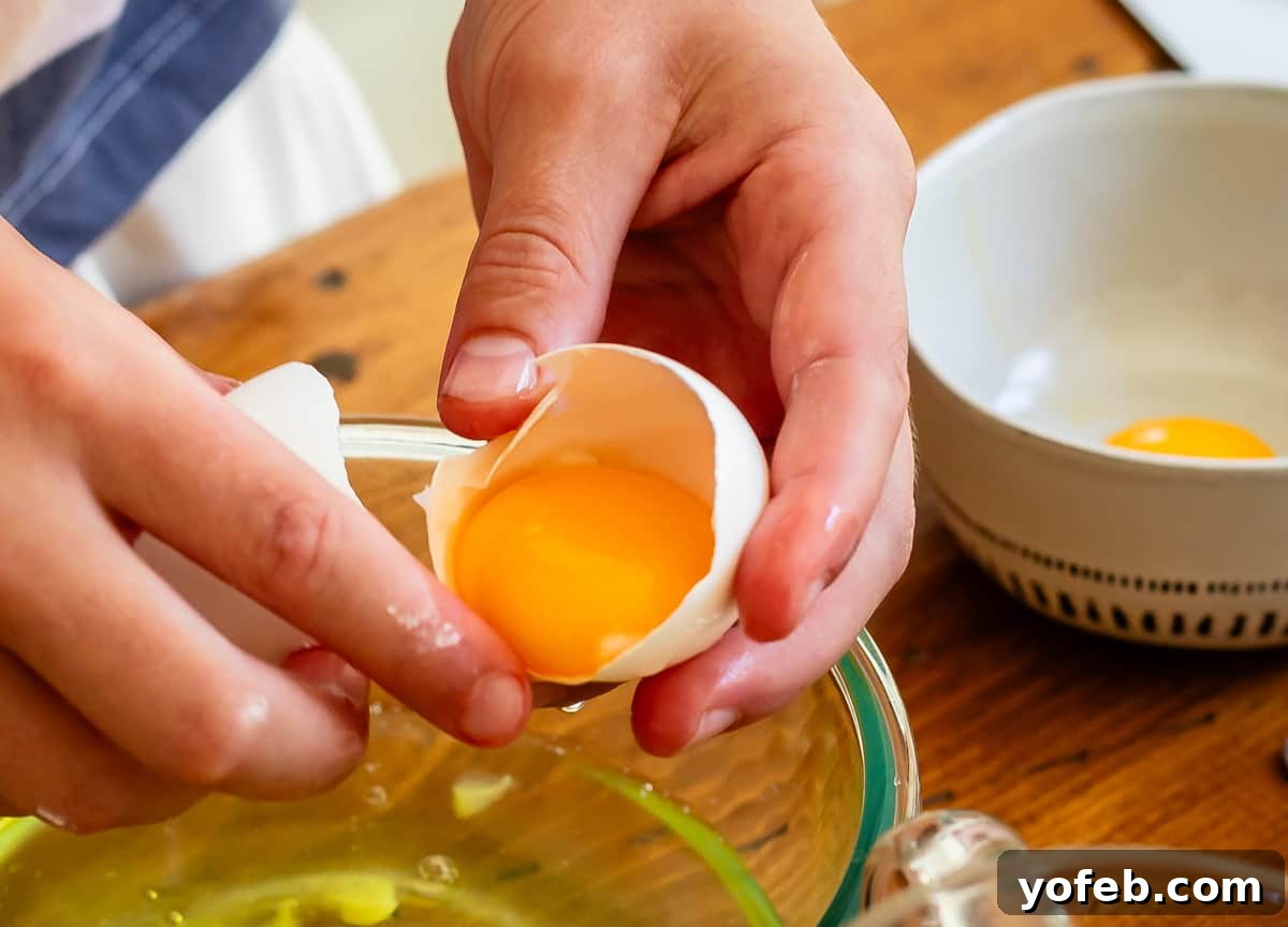 Velvety Crème Pâtissière 7 child's hands cracking an egg into a glass mixing bowl.