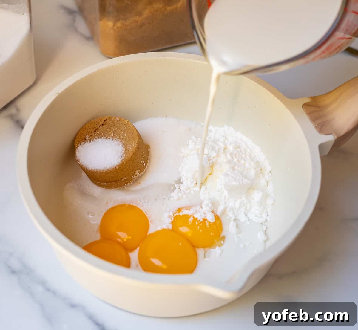 Velvety Crème Pâtissière 8 milk being poured into a bowl that has sugar and eggs in it for pastry cream.