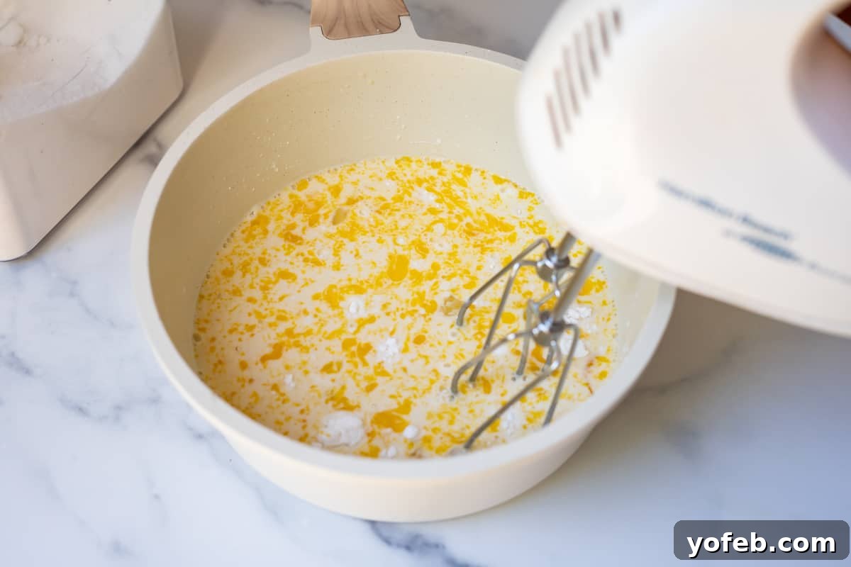 Velvety Crème Pâtissière 9 egg, sugars, and milk being mixed by a handmixer in order to make homemade pastry cream.