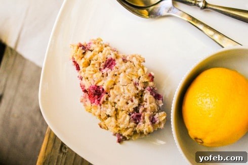 Close-up of baked oatmeal with fresh raspberries and lemon zest, inviting you to take a spoonful