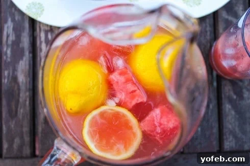 Watermelon Lemon Burst 2 Overhead shot of vibrant watermelon lemonade with fresh lemon slices in a clear pitcher on a rustic wooden table, embodying summer refreshment.