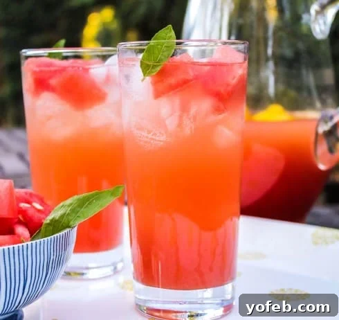 Watermelon Lemon Burst 3 Two elegant glasses of watermelon lemonade, garnished with fresh basil leaves, next to a bowl of perfectly cubed watermelon, inviting a refreshing sip.