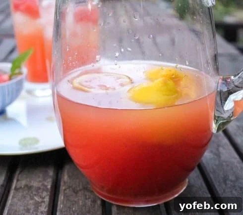 Watermelon Lemon Burst 4 A half-full pitcher of bright red watermelon lemonade, perfectly chilled and inviting, resting on a rustic wooden outdoor table, capturing the essence of summer refreshment.