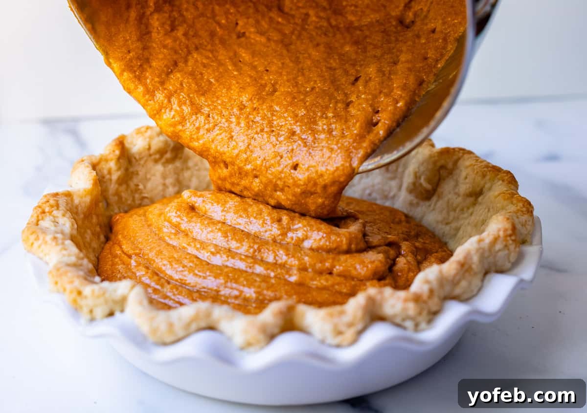 Golden Sweet Potato Pie Crowned with Salted Caramel Cream 22 pouring sweet potato pie filling from a mixing bowl into a par-baked pie shell in a ceramic dish.