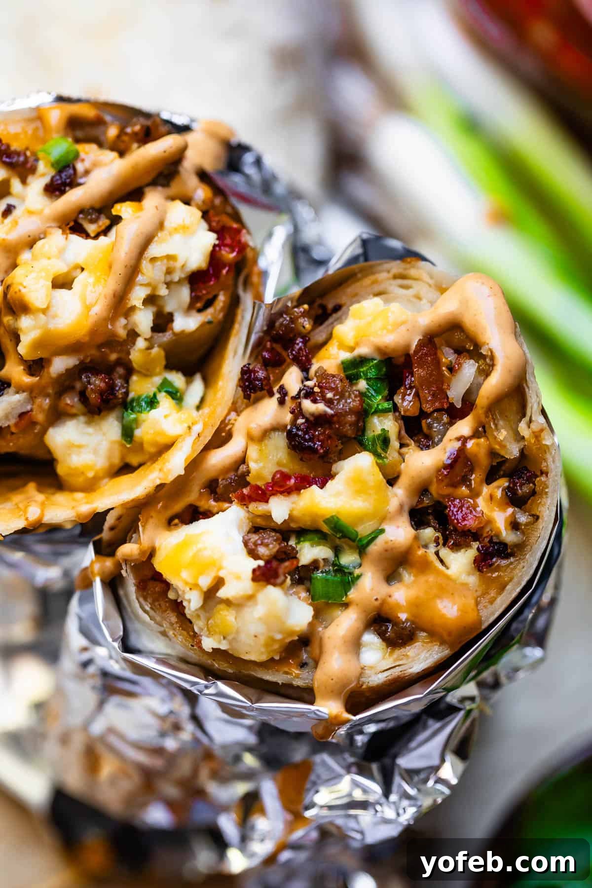 The Ultimate Make Ahead Breakfast Burrito Recipe 3 breakfast burritos wrapped in aluminum foil close up.