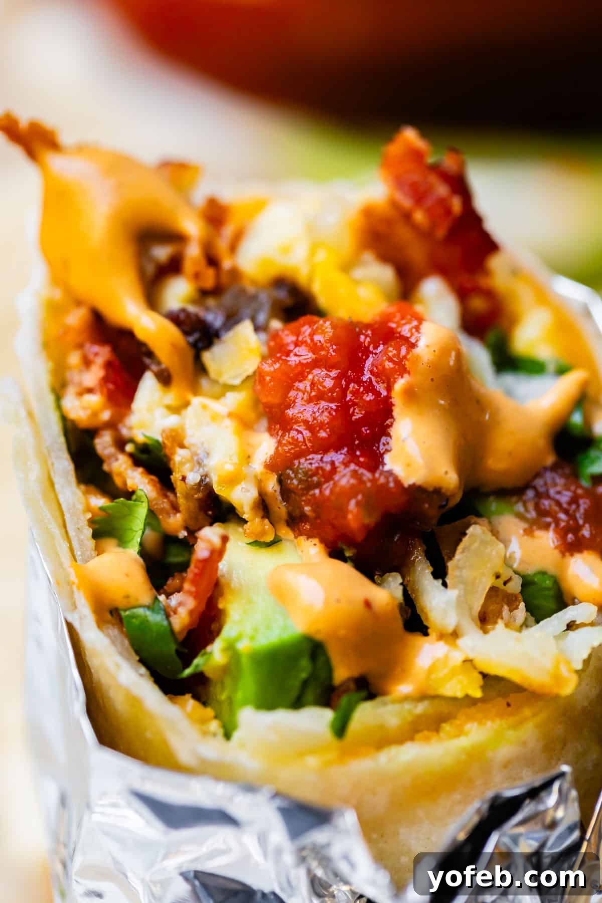 The Ultimate Make Ahead Breakfast Burrito Recipe 26 Breakfast burrito with bite out of it and salsa.