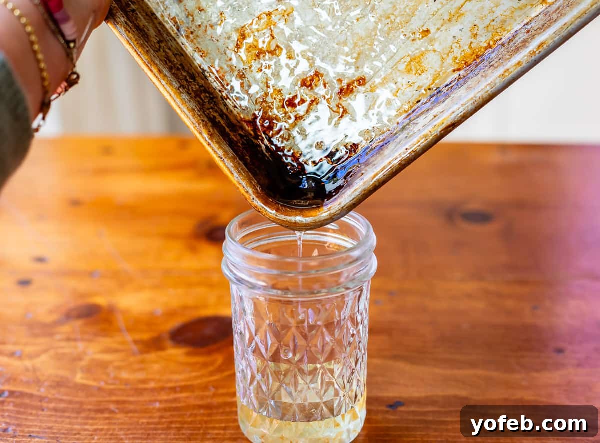 The Ultimate Make Ahead Breakfast Burrito Recipe 9 pouring warm bacon grease from sheet pan into a jar for saving to use later.