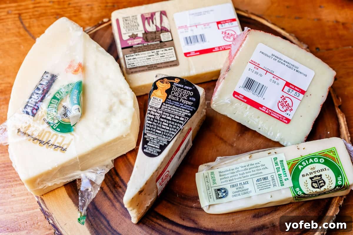 Crafting the Perfect Charcuterie Board 12 Arrangement of hard cheese on wood board including pecorino romano, black pepper toscano, white cheddar, manchego, and asiago with rosemary.
