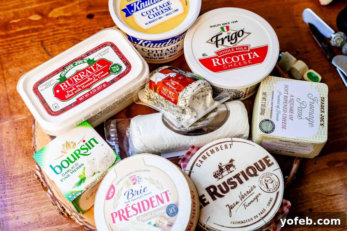 Crafting the Perfect Charcuterie Board 15 Arrange of soft cheeses in packaging on wooden board including burrata, boursin, brie, camembert, goat, ricotta, cottage, and pave.