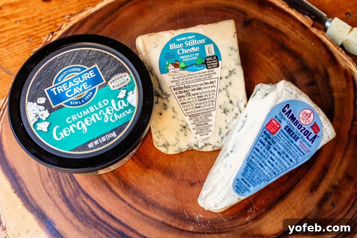 Crafting the Perfect Charcuterie Board 16 Arrangement of crumbly, stinky cheeses in packaging on wooden board including gorgonzola, blue stilton, and triple cream.