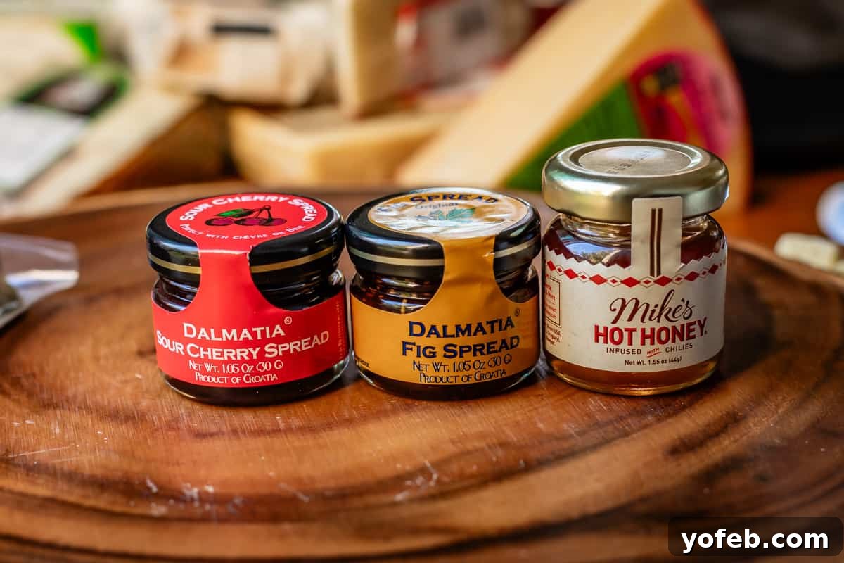 Crafting the Perfect Charcuterie Board 26 three small jars of spread including sour cherry, fig, and hot honey on wooden board for display.