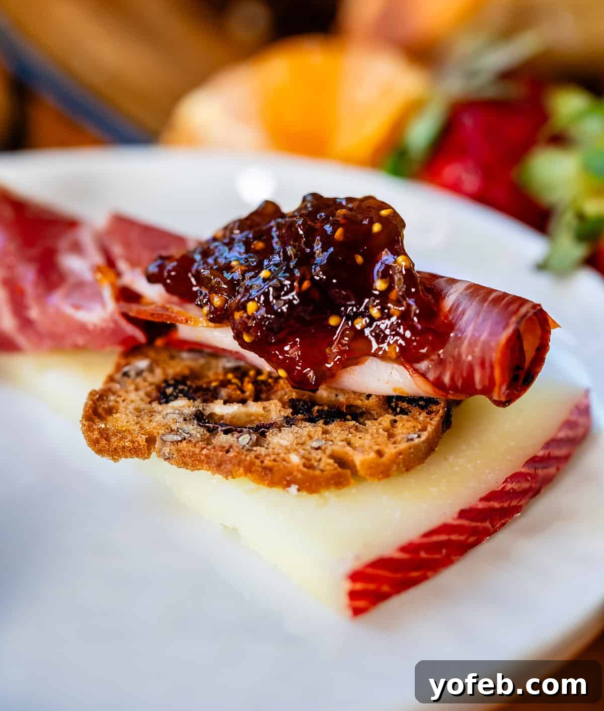 Crafting the Perfect Charcuterie Board 28 Delectable morsel of cheese, sweet cracker, deli meat, and fig jam close up on white plate.