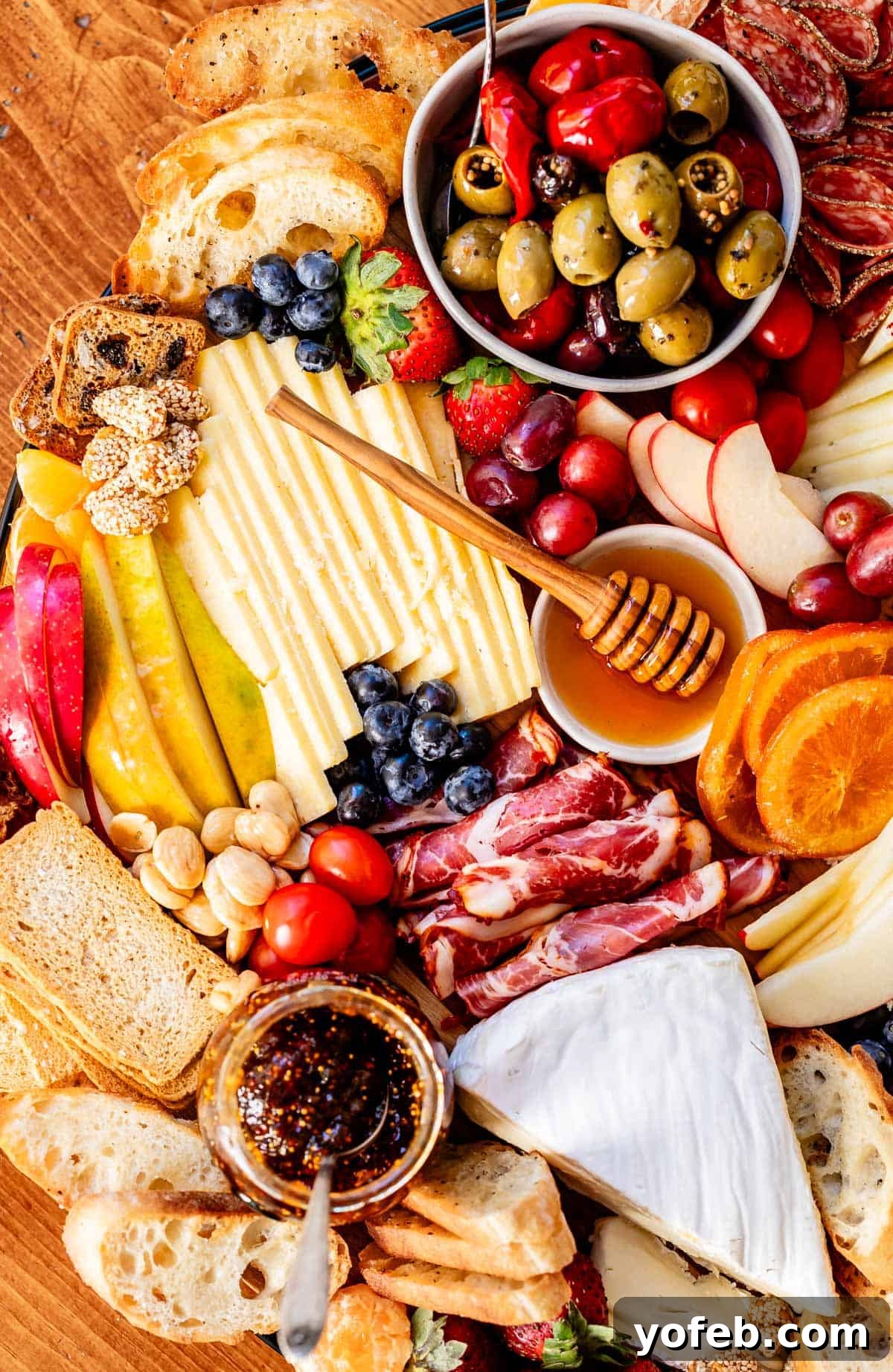 Crafting the Perfect Charcuterie Board 29 Picture of a charcuterie board with cheese, meat, fruits, honey, oranges, blueberries, etc.
