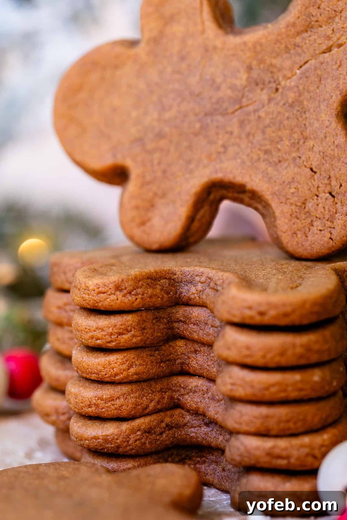 Perfectly Soft Chewy Gingerbread Men That Hold Their Shape 10 A stack of perfectly baked gingerbread cookies, with the top cookie being gently pulled from the pile by a hand, emphasizing their intact shape.