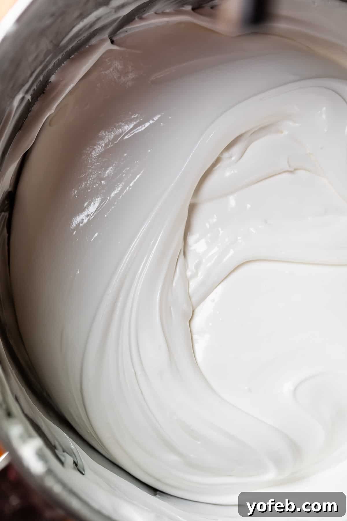 Beginner's Guide to Perfect Royal Icing 19 white toothpaste like consistency icing in a metal kitchen aid mixing bowl.