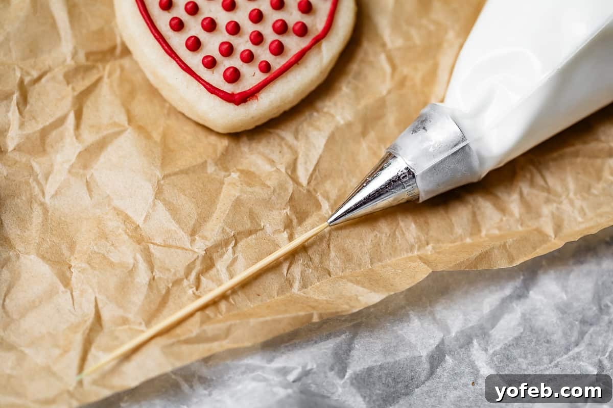 Beginner's Guide to Perfect Royal Icing 29 close up of a toothpick inserted into a piping tip to get it unclogged.