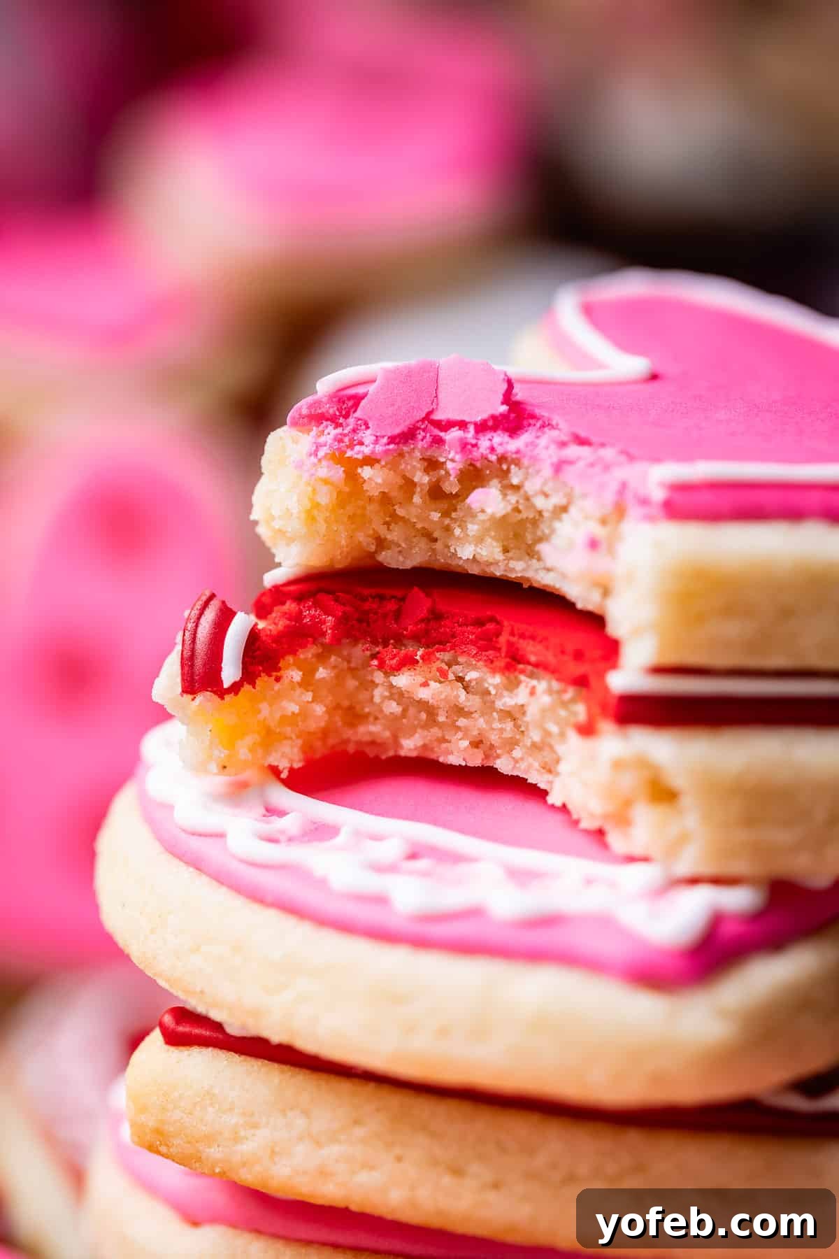 Beginner's Guide to Perfect Royal Icing 8 bite taken out of two red and pink sugar cookies, frosted with royal icing.