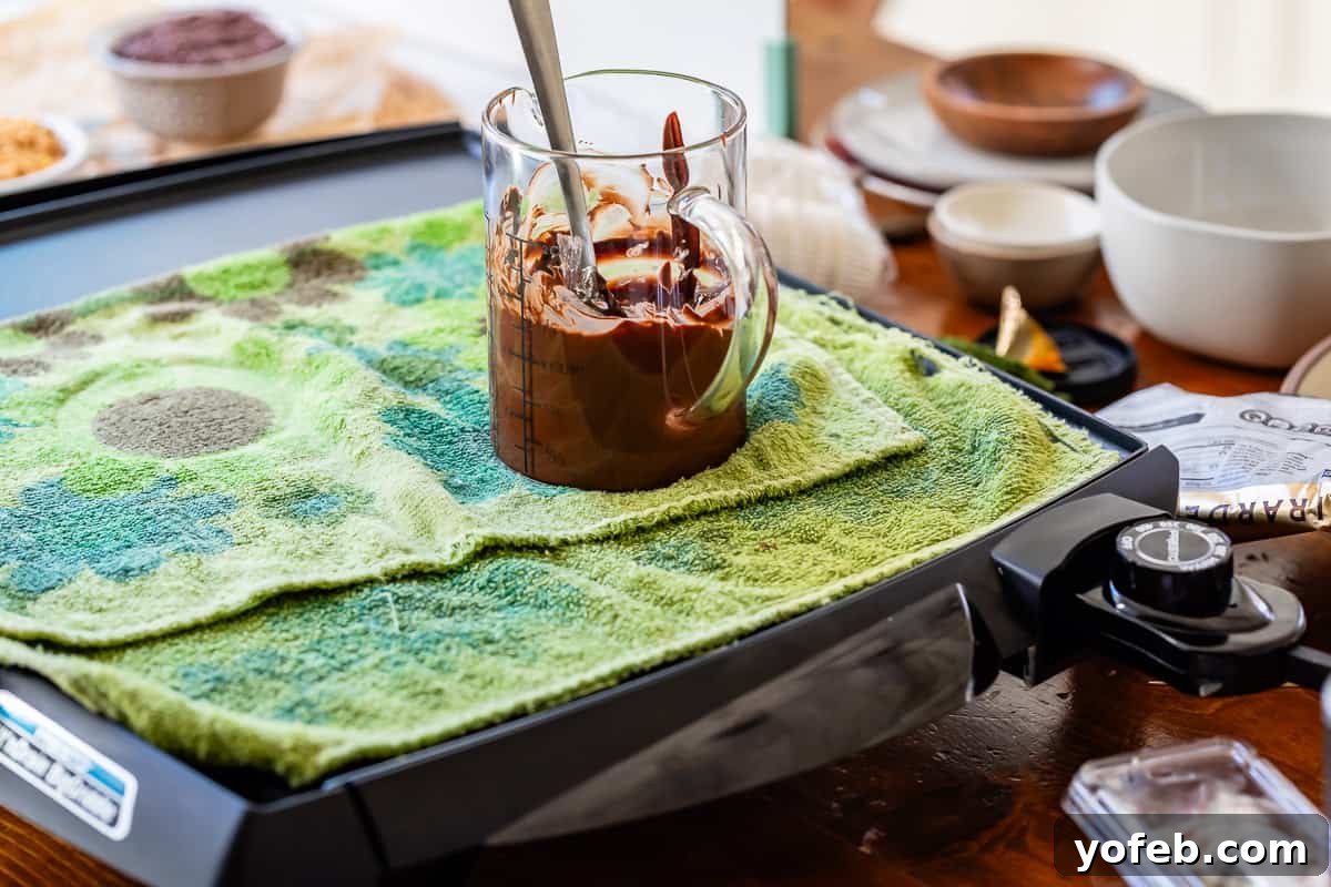 Irresistible Buckeye Ball Recipe 17 Glass measuring cup full of melted chocolate on an electric griddle.