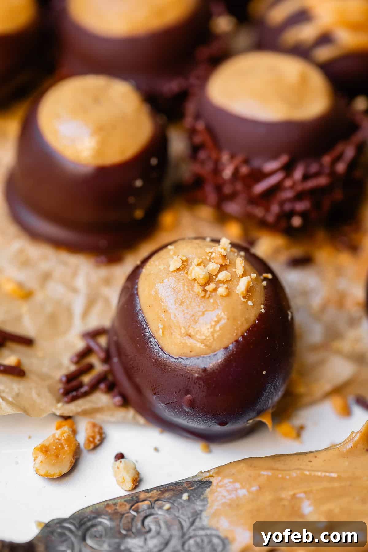 Irresistible Buckeye Ball Recipe 26 A buckeye candy with nuts sprinkled on top on parchment paper, showing signs of sweating.