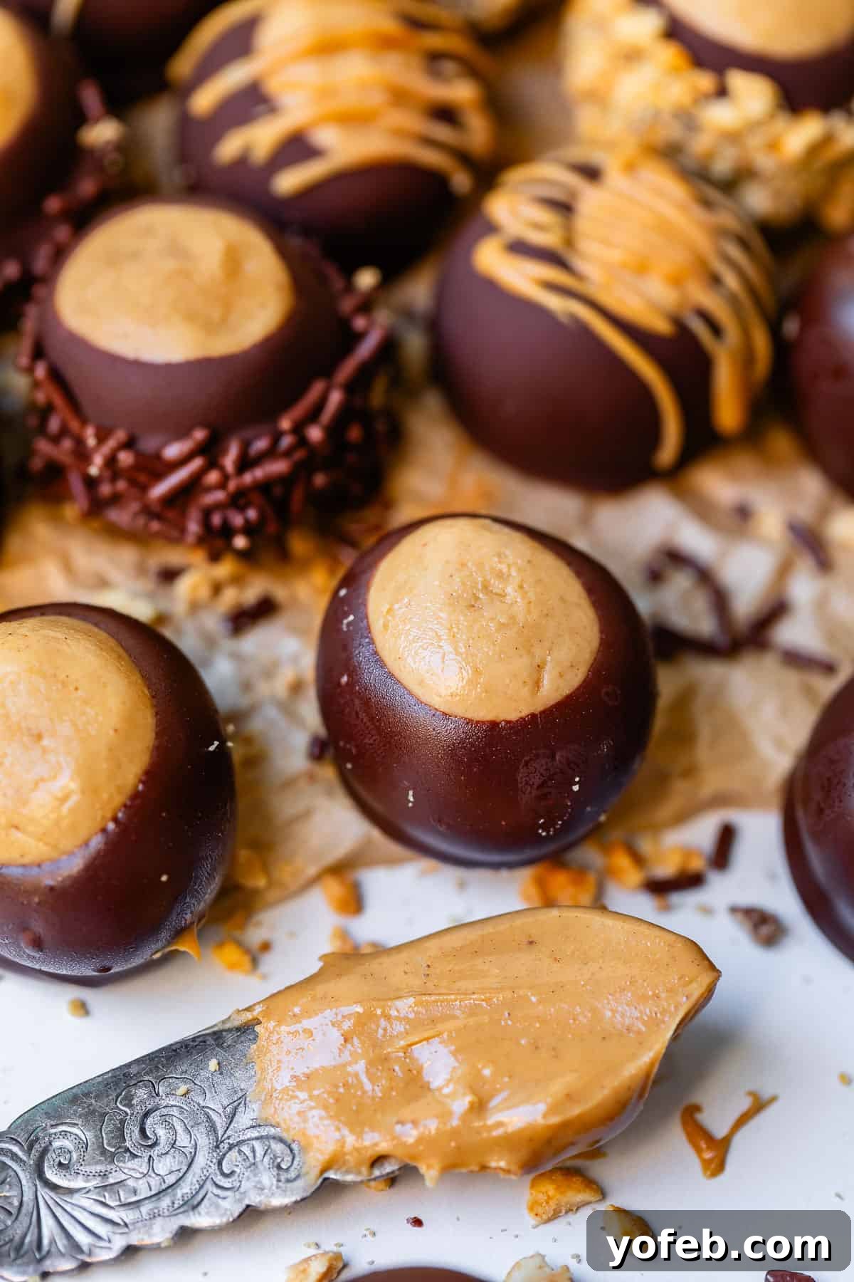 Irresistible Buckeye Ball Recipe 27 Buckeye balls lined up on parchment paper, with a butter knife with peanut butter on it.