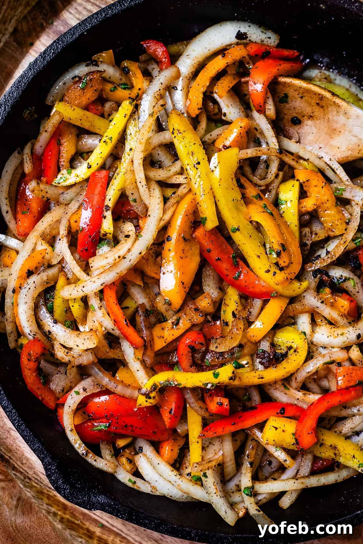 My Chicken Fajitas Awakening 17 looking down into a cast iron skillet filled with sliced bell pepper and onion in marinade.