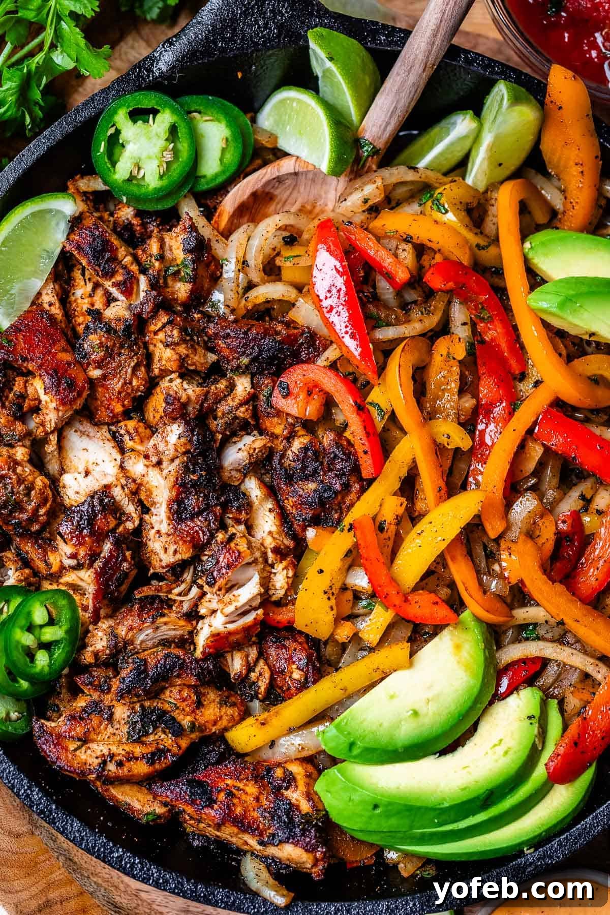 My Chicken Fajitas Awakening 20 cast iron skillet filled with blackened chicken on one side and peppers and onions on the other.