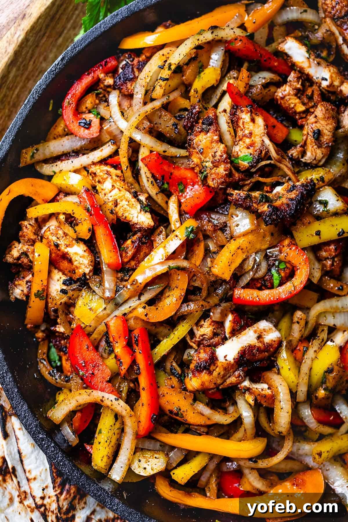 My Chicken Fajitas Awakening 3 looking down at a cast iron skillet filled with blackened chicken, onions, and peppers.